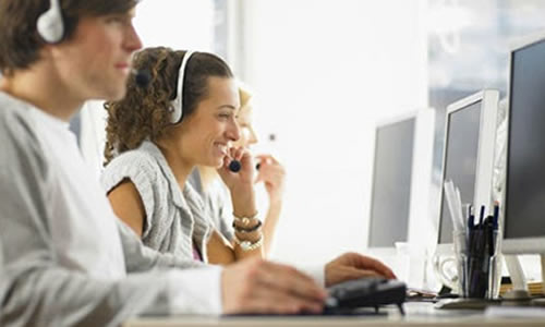 Atendentes de central de atendimento com fone de ouvido em frente ao computador